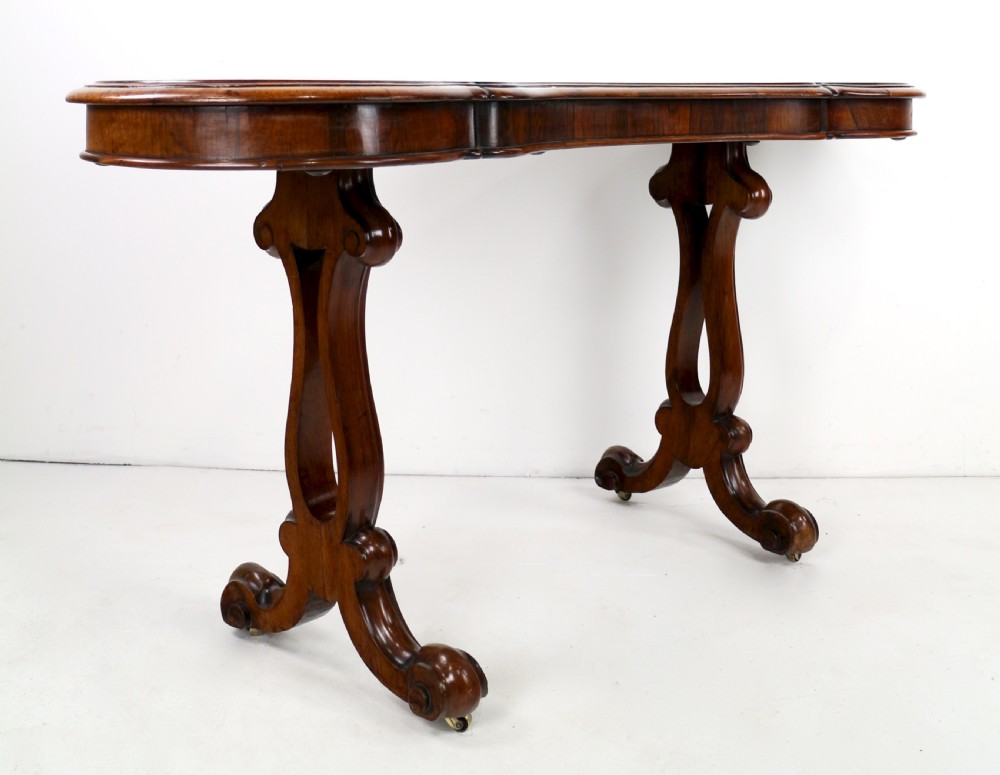 A Victorian rosewood kidney-shaped writing table with a figured timber top supported by carved lyre legs ending in scroll feet. View XVII