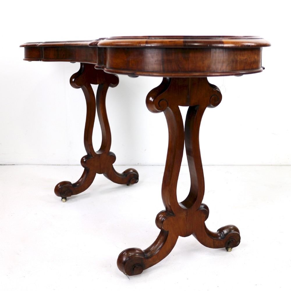 A Victorian rosewood kidney-shaped writing table with a figured timber top supported by carved lyre legs ending in scroll feet. View XVIII