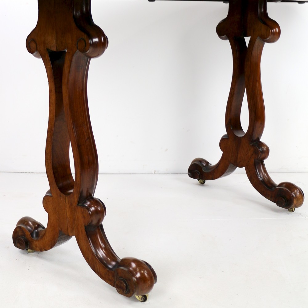A Victorian rosewood kidney-shaped writing table with a figured timber top supported by carved lyre legs ending in scroll feet. View XIX