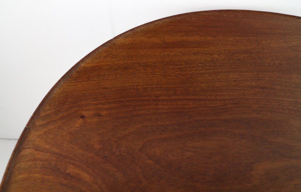 An Early Georgian mahogany tripod table featuring a circular dish top tilted vertically above a turned stem and cabriole legs with pad feet. View XI