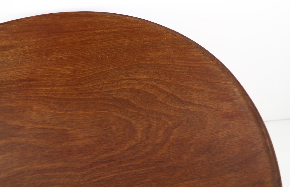 An Early Georgian mahogany tripod table featuring a circular dish top tilted vertically above a turned stem and cabriole legs with pad feet. View XIII