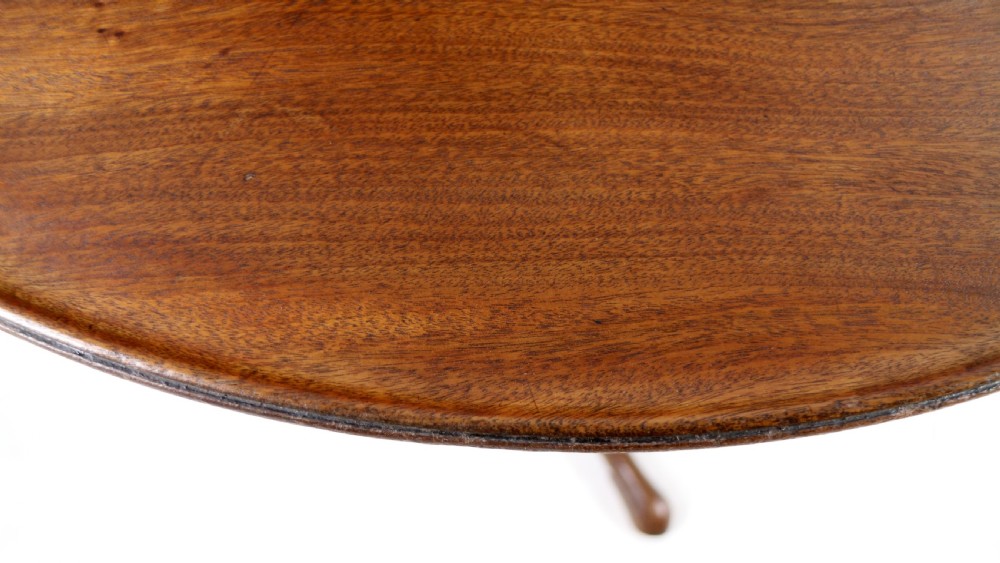 An Early Georgian mahogany tripod table featuring a circular dish top tilted vertically above a turned stem and cabriole legs with pad feet. View XVIII