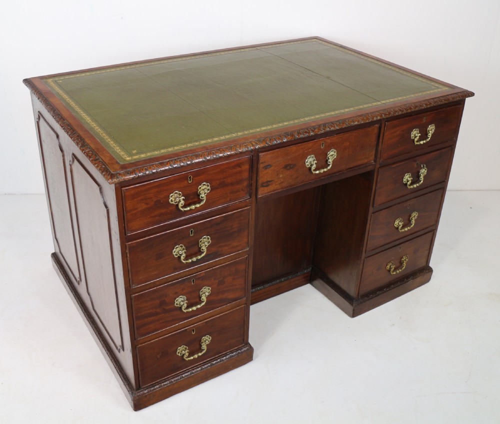 A dark mahogany kneehole library desk featuring multiple drawers with brass drop handles and panelled sides. View II