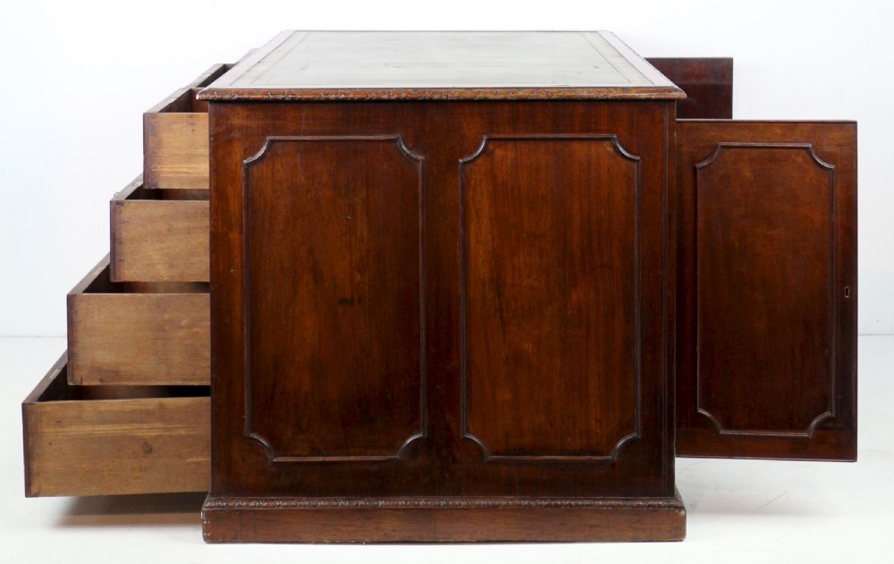 A dark mahogany kneehole library desk featuring multiple drawers with brass drop handles and panelled sides. View VII
