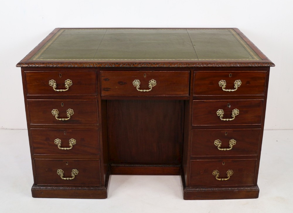 A dark mahogany kneehole library desk featuring multiple drawers with brass drop handles and panelled sides. View VIII