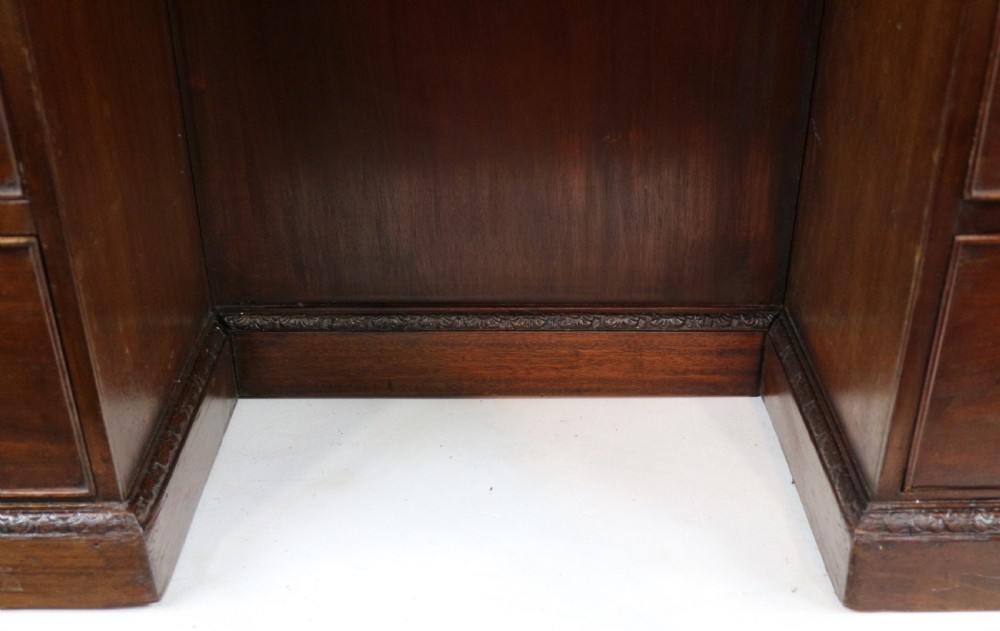 A dark mahogany kneehole library desk featuring multiple drawers with brass drop handles and panelled sides. View XI