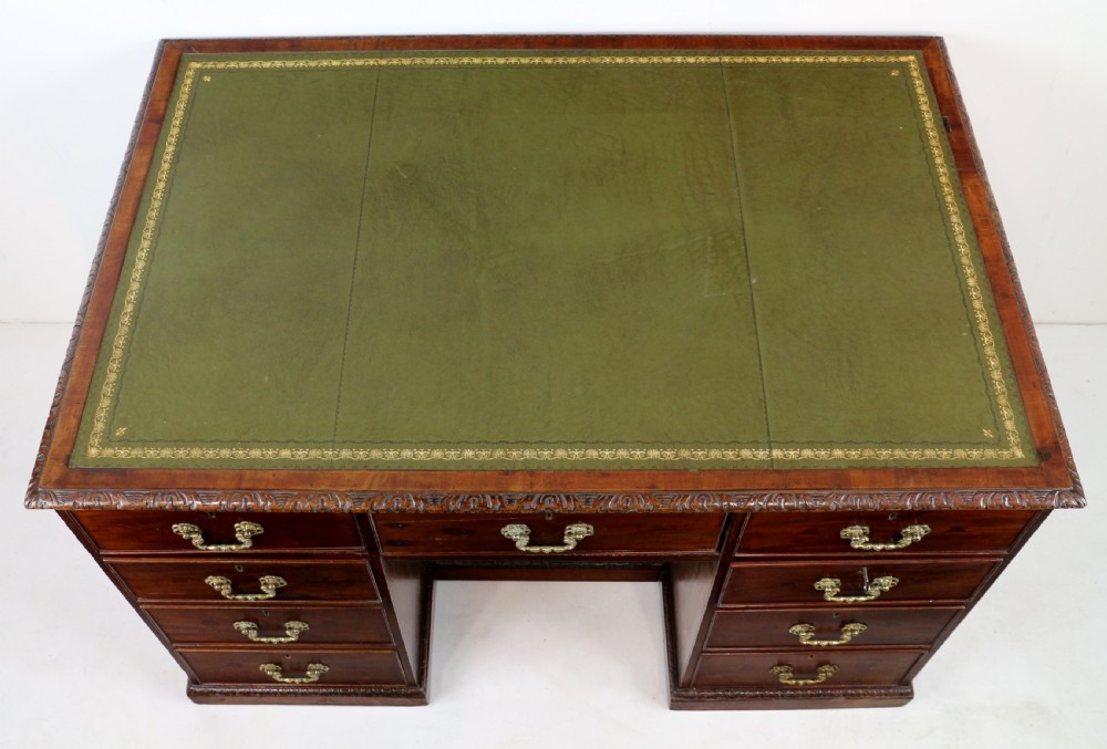 A dark mahogany kneehole library desk featuring multiple drawers with brass drop handles and panelled sides. View XIII