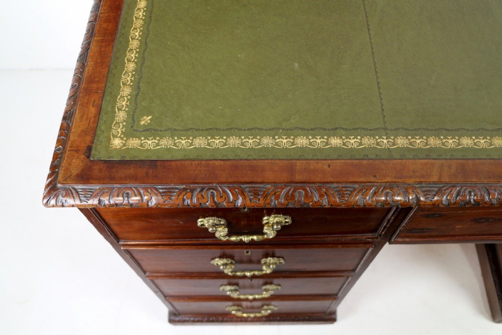 A dark mahogany kneehole library desk featuring multiple drawers with brass drop handles and panelled sides. View XIV