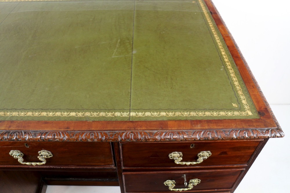 A dark mahogany kneehole library desk featuring multiple drawers with brass drop handles and panelled sides. View XV