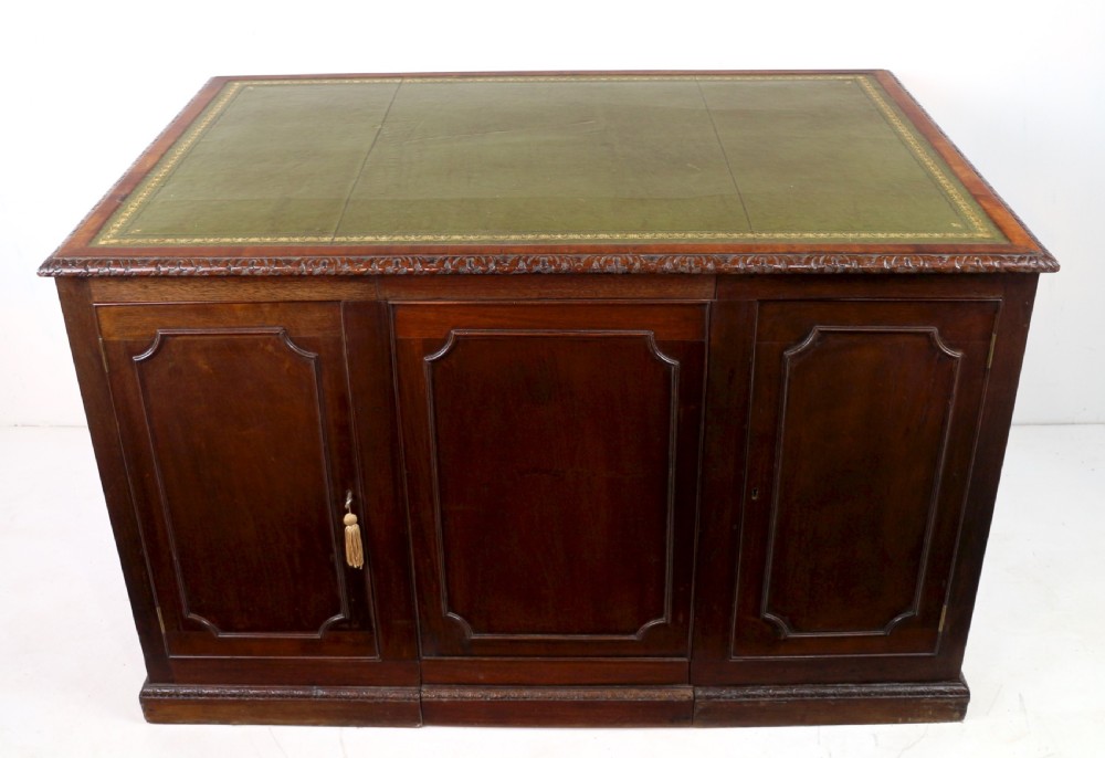 A dark mahogany kneehole library desk featuring multiple drawers with brass drop handles and panelled sides. View XXI