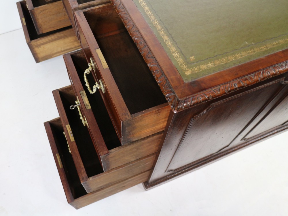 A dark mahogany kneehole library desk featuring multiple drawers with brass drop handles and panelled sides. View XXIX