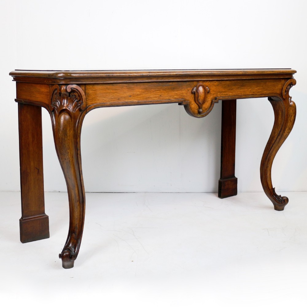 An antique William IV oak hall table featuring carved cabriole front legs and a central carved apron accent.