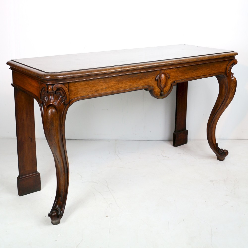 An antique William IV oak hall table featuring carved cabriole front legs and a central carved apron accent. View XVI