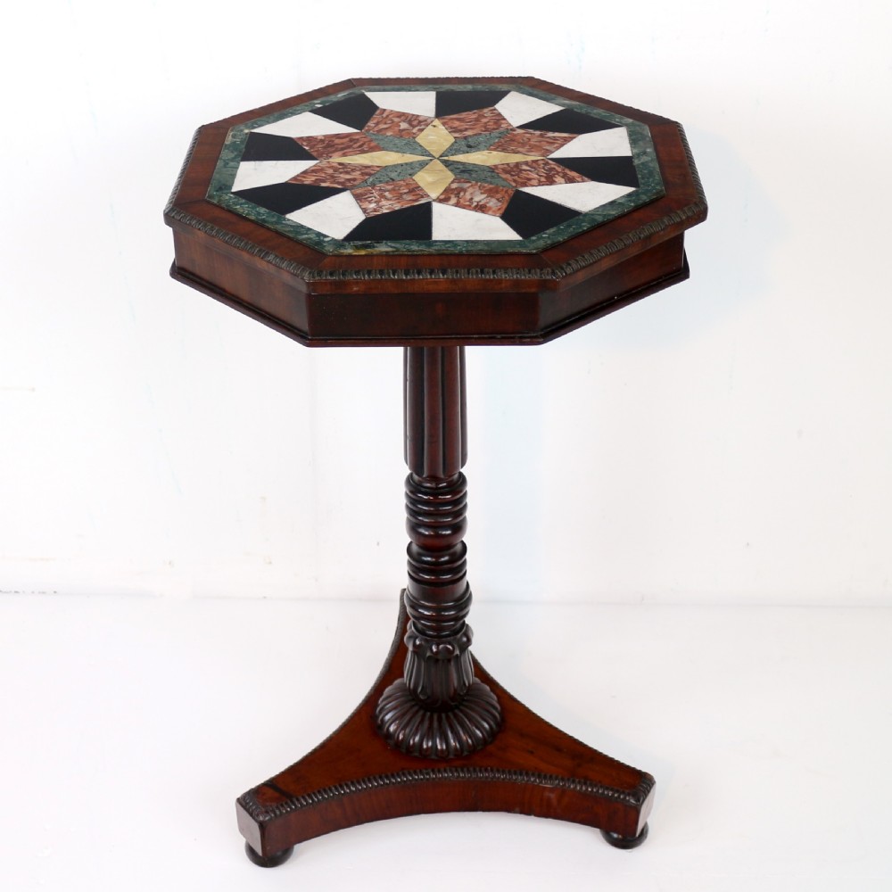 An octagonal Regency mahogany side table featuring a geometric star-patterned specimen marble top supported by a reeded column and triform base.