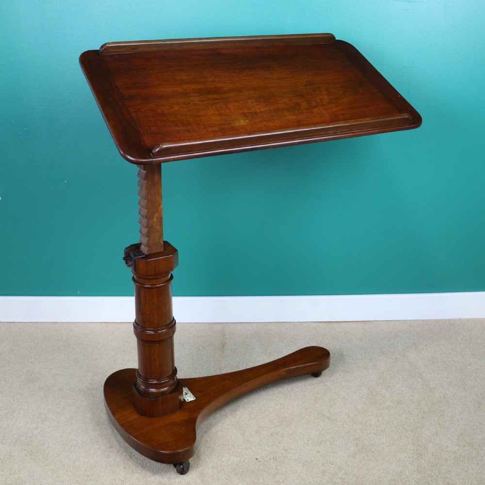 A Victorian mahogany adjustable reading table featuring a ratchet height mechanism, tilted top ledge, turned pedestal, and curved base on castors. View V