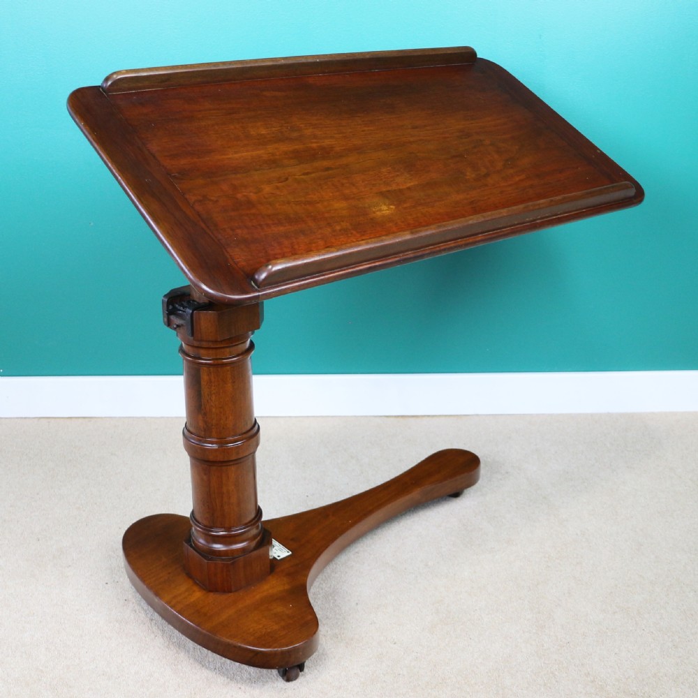 A Victorian mahogany adjustable reading table featuring a ratchet height mechanism, tilted top ledge, turned pedestal, and curved base on castors. View II