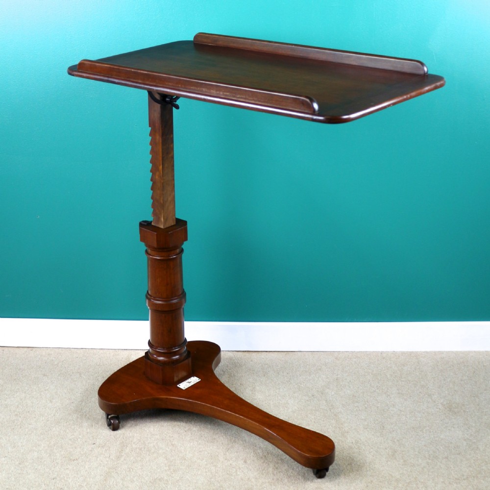 A Victorian mahogany adjustable reading table featuring a ratchet height mechanism, tilted top ledge, turned pedestal, and curved base on castors. View VI