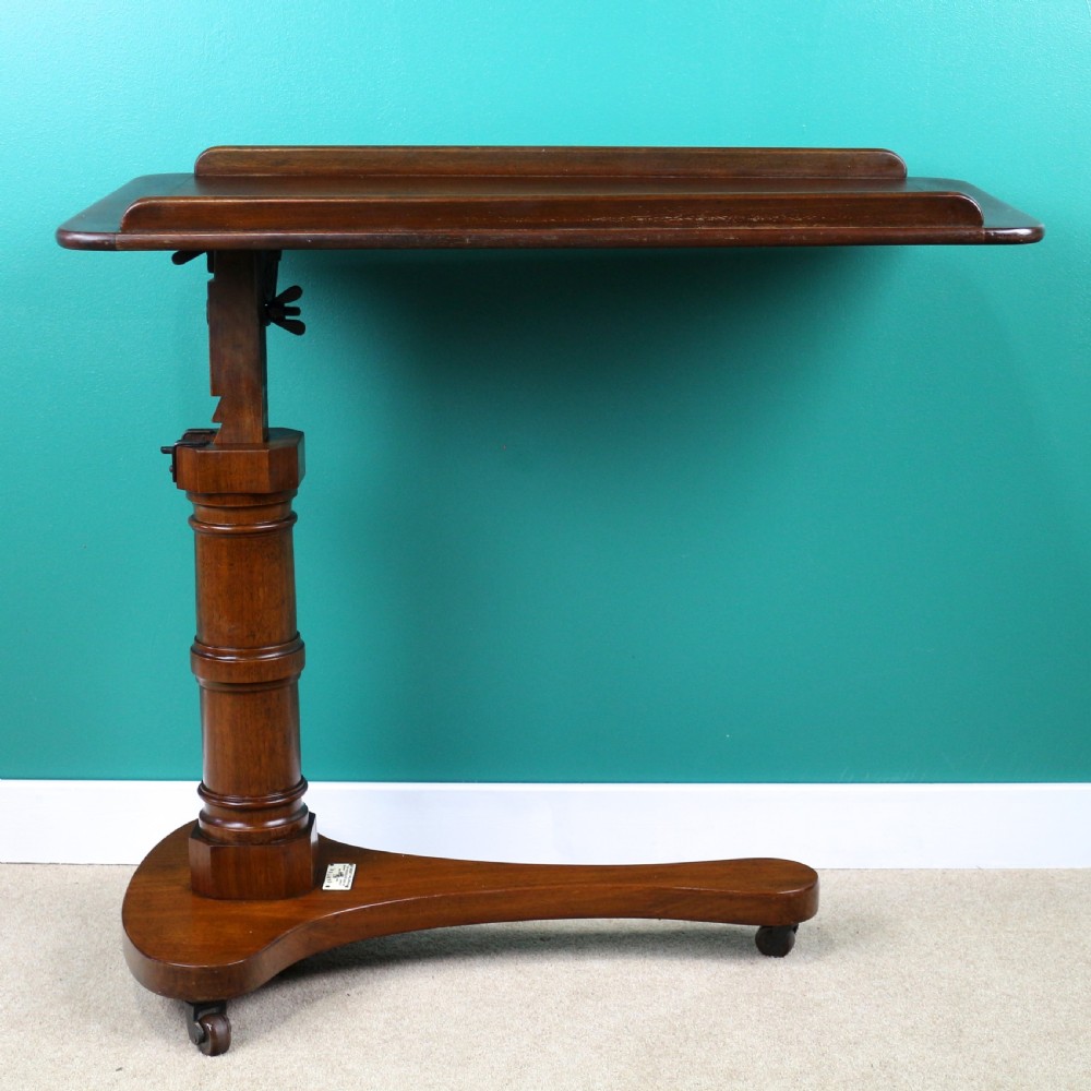 A Victorian mahogany adjustable reading table featuring a ratchet height mechanism, tilted top ledge, turned pedestal, and curved base on castors. View VII