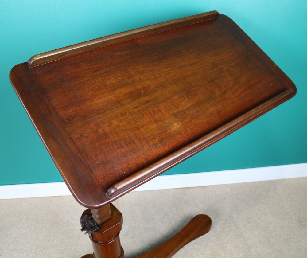 A Victorian mahogany adjustable reading table featuring a ratchet height mechanism, tilted top ledge, turned pedestal, and curved base on castors. View IX