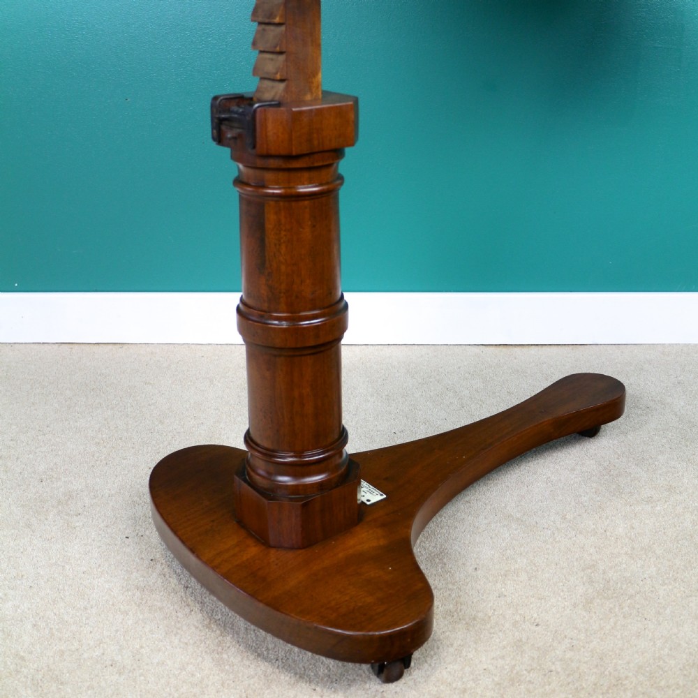 A Victorian mahogany adjustable reading table featuring a ratchet height mechanism, tilted top ledge, turned pedestal, and curved base on castors. View XII