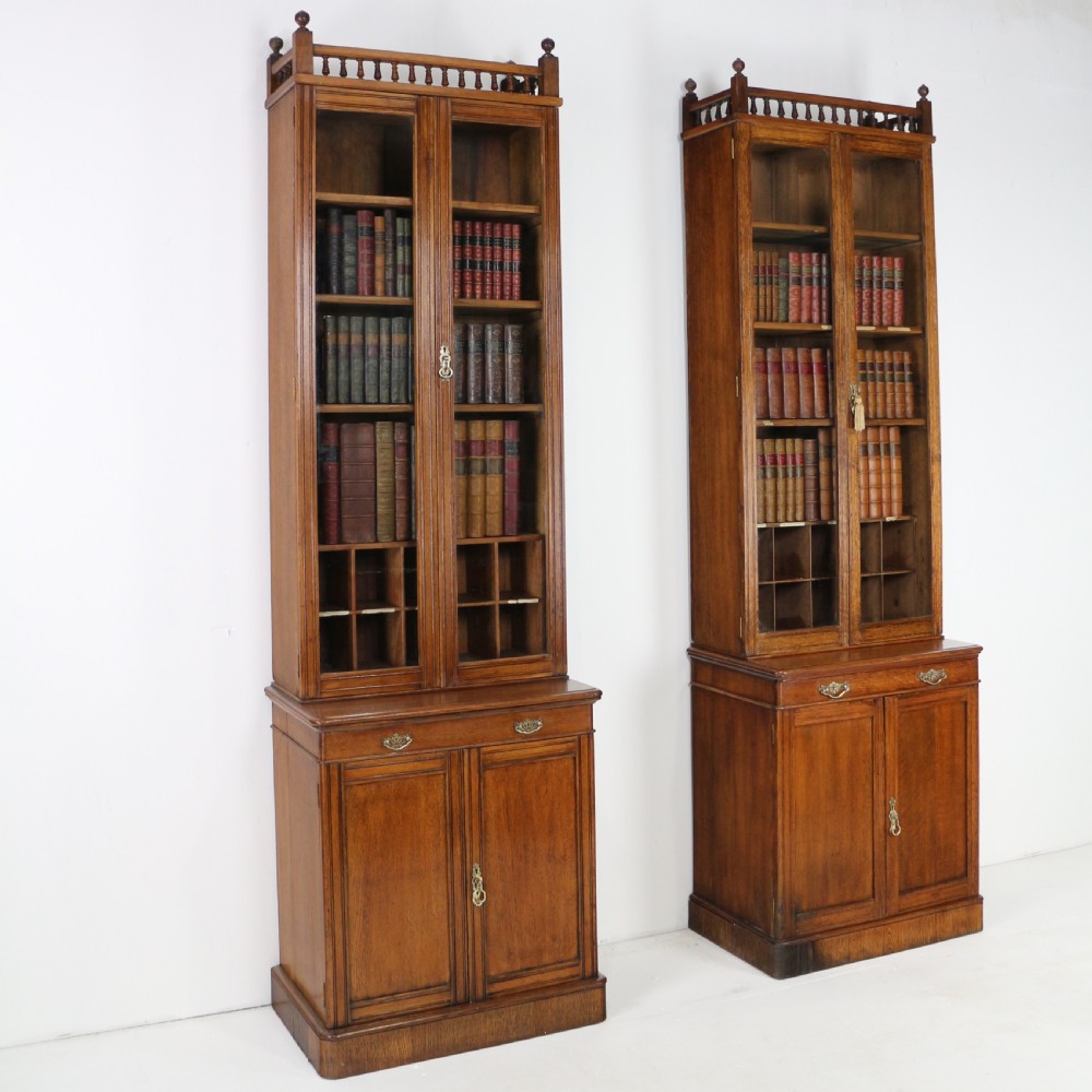 A pair of tall, narrow late Victorian oak glazed bookcases with spindle gallery tops and lower panelled cupboard bases. View III