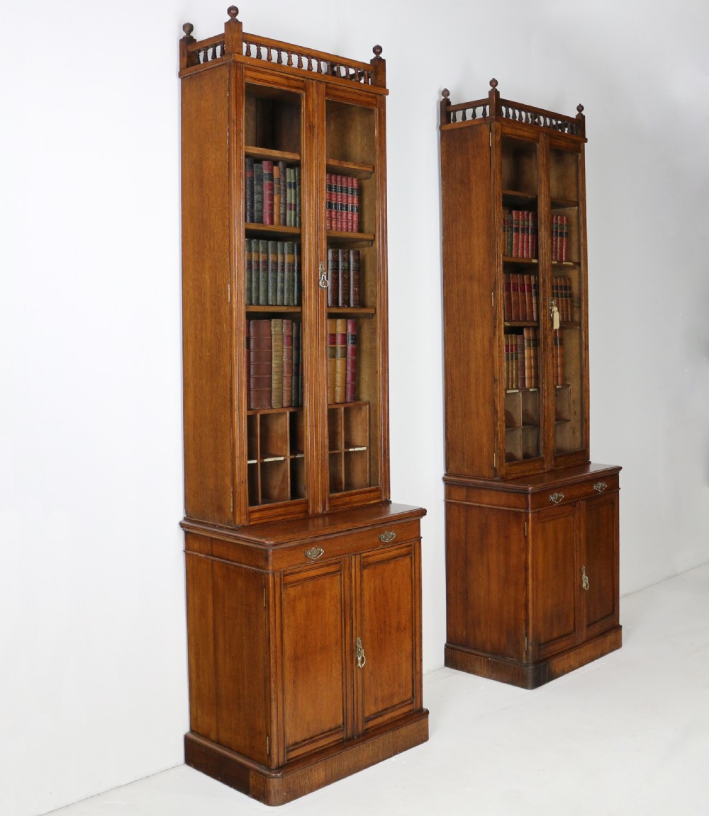 A pair of tall, narrow late Victorian oak glazed bookcases with spindle gallery tops and lower panelled cupboard bases. View VII