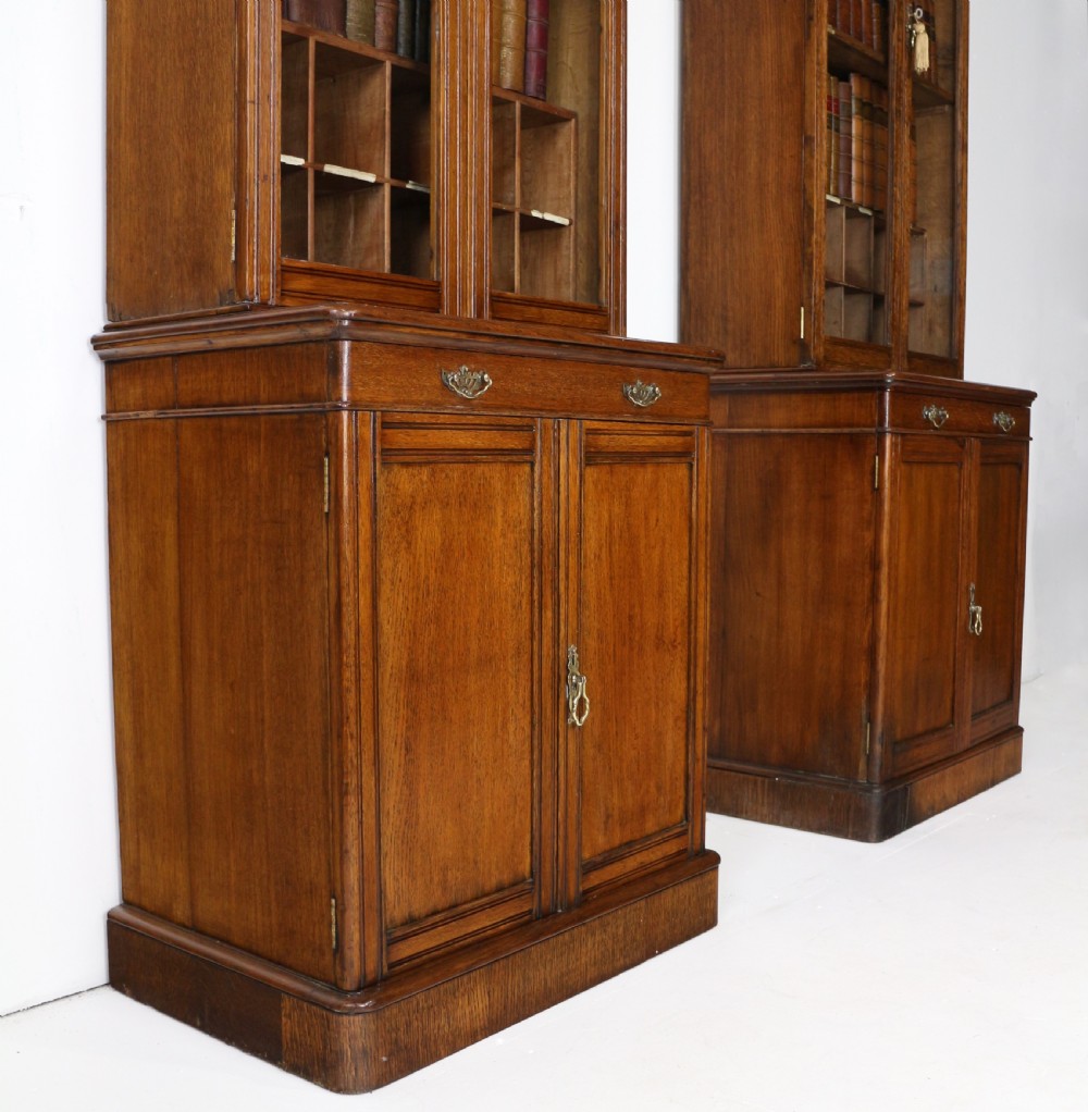 A pair of tall, narrow late Victorian oak glazed bookcases with spindle gallery tops and lower panelled cupboard bases. View IX