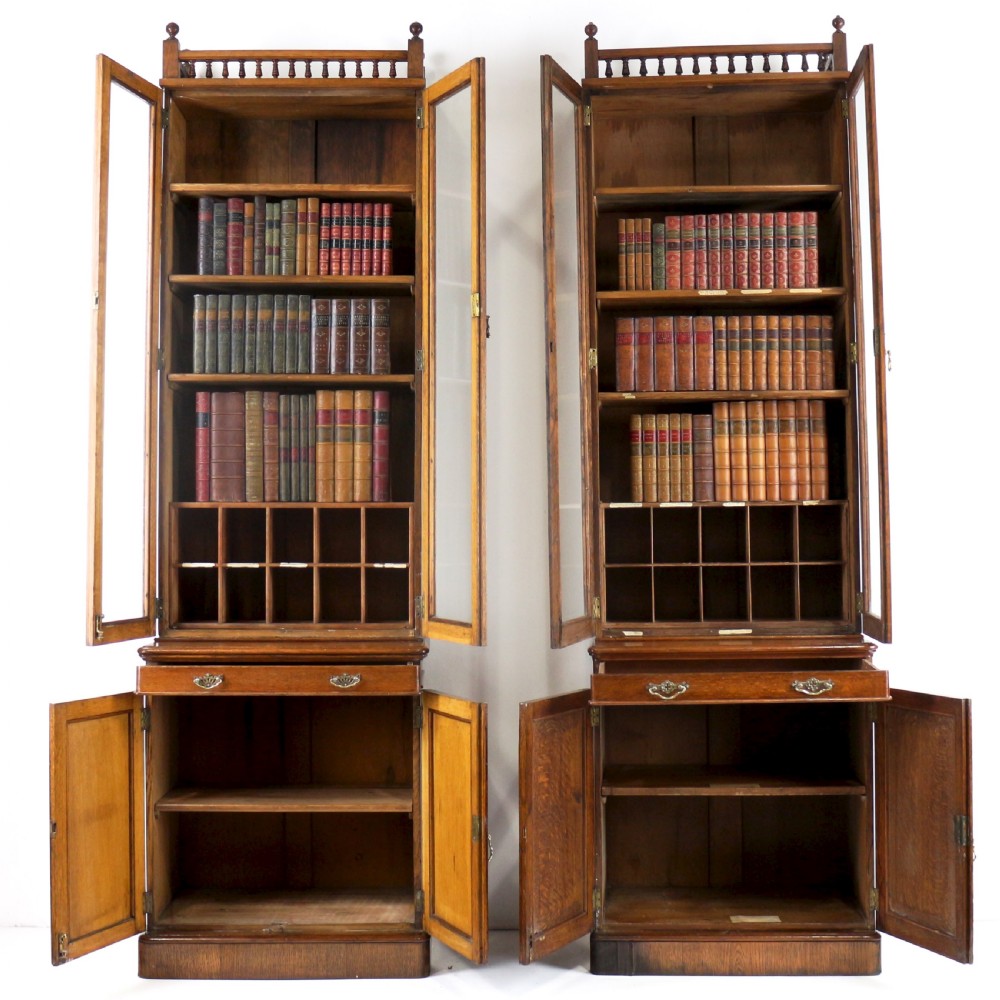 A pair of tall, narrow late Victorian oak glazed bookcases with spindle gallery tops and lower panelled cupboard bases. View X