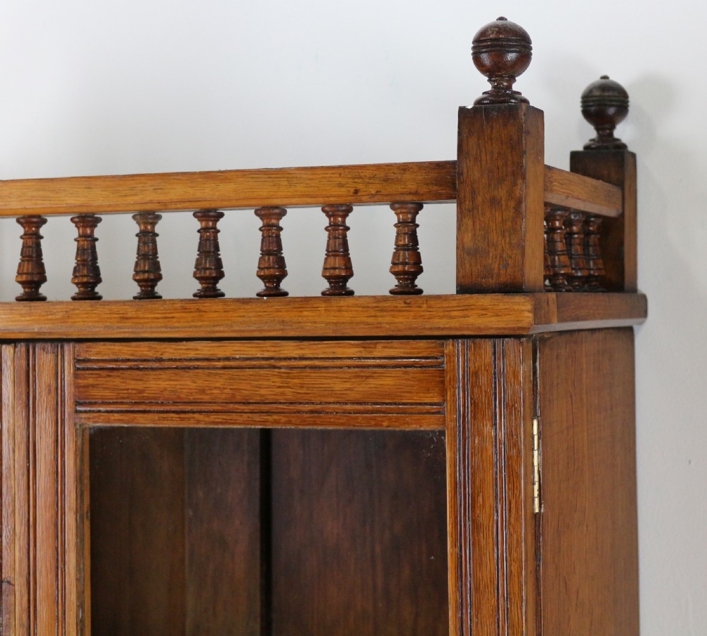 A pair of tall, narrow late Victorian oak glazed bookcases with spindle gallery tops and lower panelled cupboard bases. View XIV