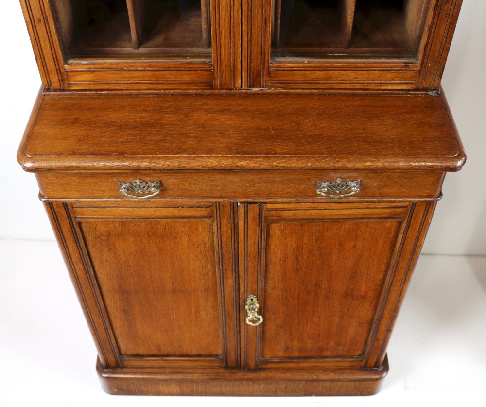 A pair of tall, narrow late Victorian oak glazed bookcases with spindle gallery tops and lower panelled cupboard bases. View XX