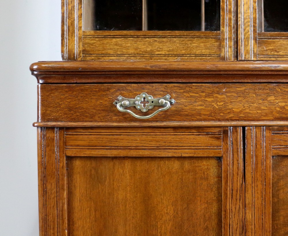A pair of tall, narrow late Victorian oak glazed bookcases with spindle gallery tops and lower panelled cupboard bases. View XXII