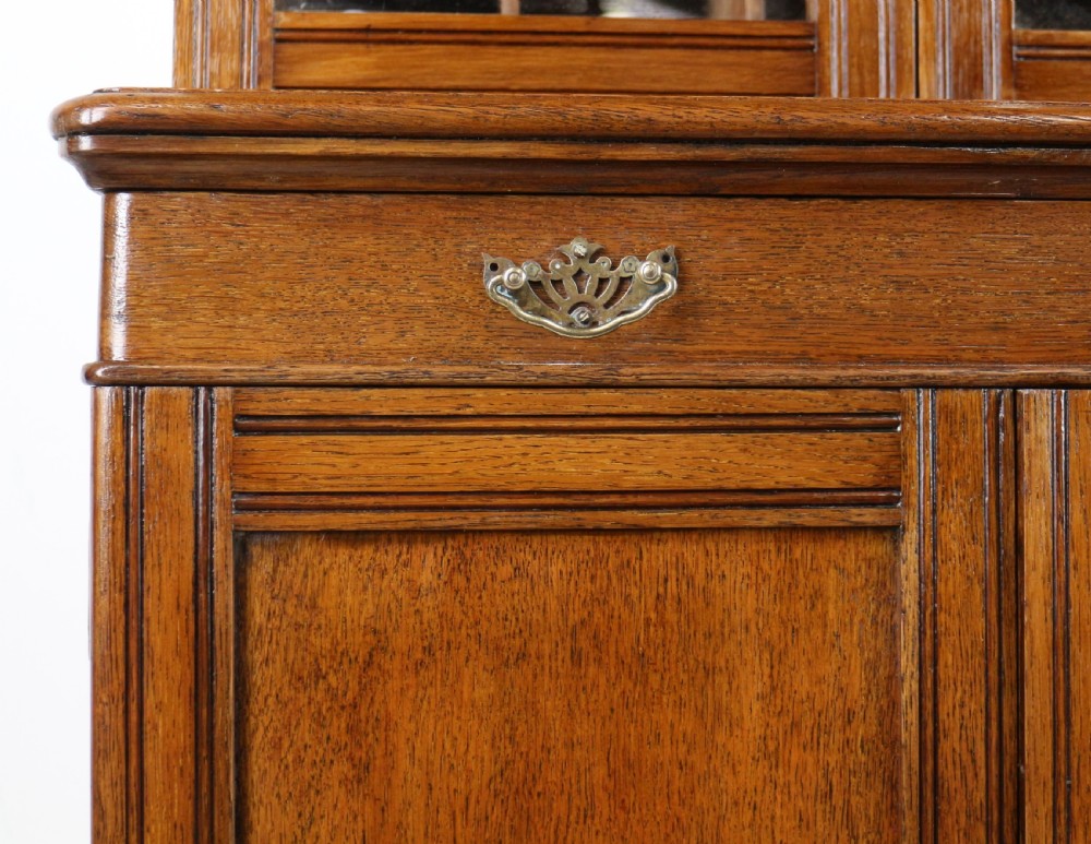 A pair of tall, narrow late Victorian oak glazed bookcases with spindle gallery tops and lower panelled cupboard bases. View XXIII