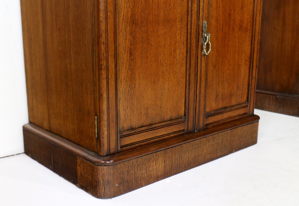 A pair of tall, narrow late Victorian oak glazed bookcases with spindle gallery tops and lower panelled cupboard bases. View XXV