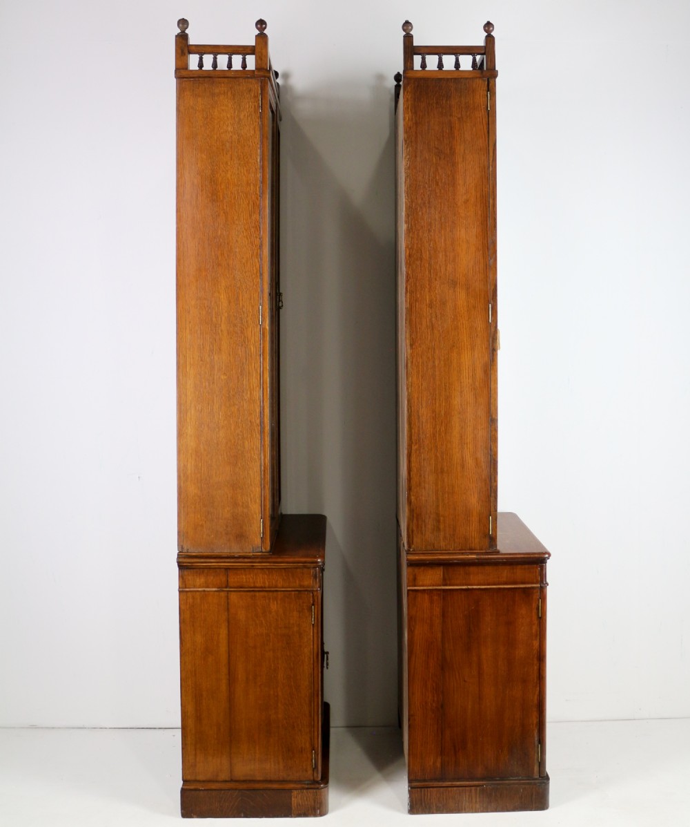 A pair of tall, narrow late Victorian oak glazed bookcases with spindle gallery tops and lower panelled cupboard bases. View XXVI
