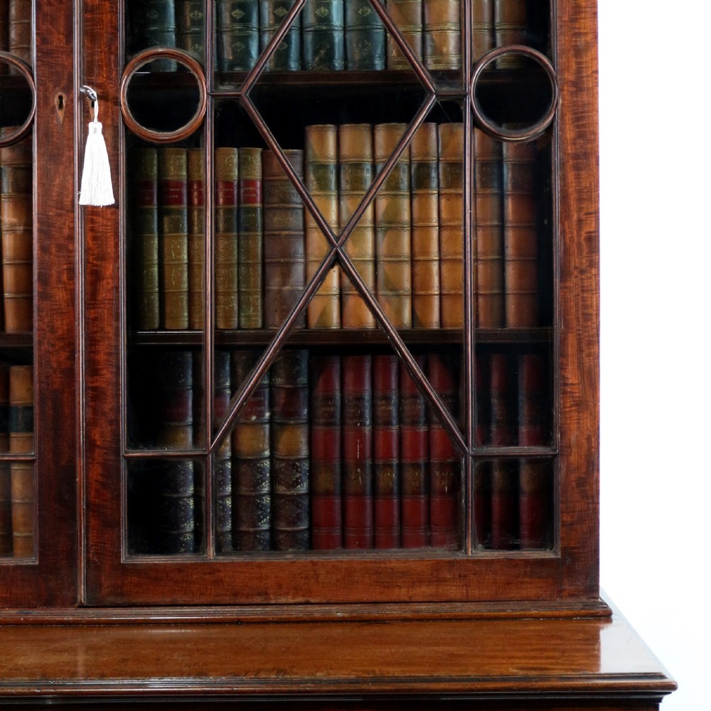 A George III mahogany secretaire bookcase featuring twin astragal glazed doors above a fitted writing drawer and lower panelled doors. View IX