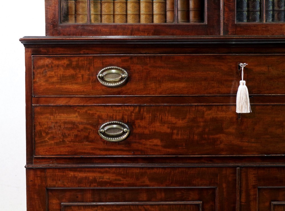 A George III mahogany secretaire bookcase featuring twin astragal glazed doors above a fitted writing drawer and lower panelled doors. View X