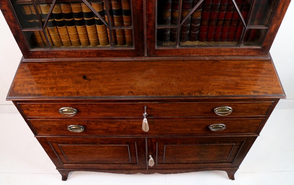 A George III mahogany secretaire bookcase featuring twin astragal glazed doors above a fitted writing drawer and lower panelled doors. View XIV