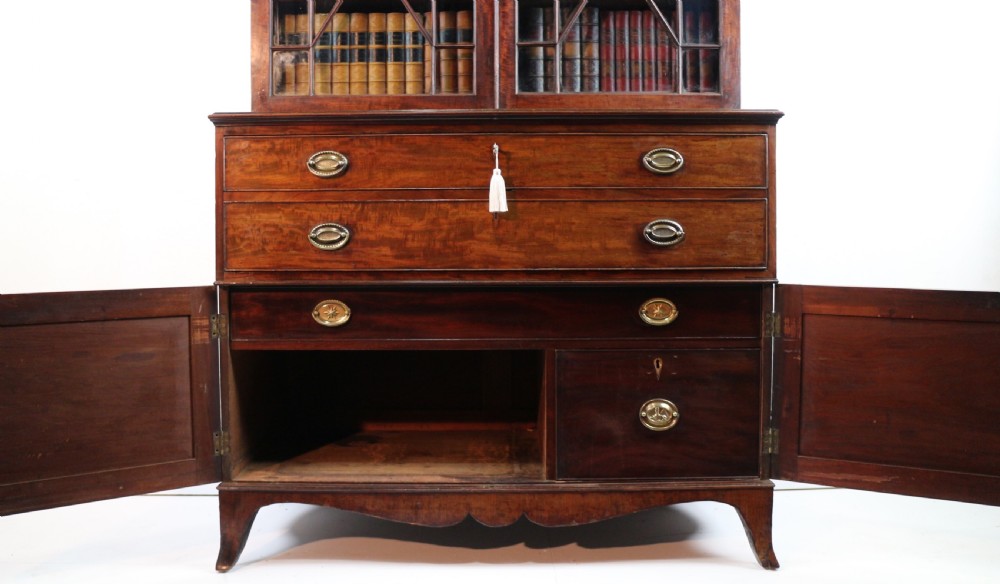 A George III mahogany secretaire bookcase featuring twin astragal glazed doors above a fitted writing drawer and lower panelled doors. View XXX