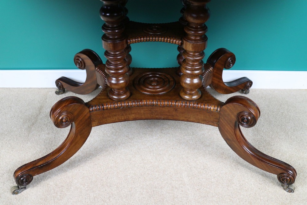 A Regency mahogany and rosewood crossbanded sofa table featuring drop leaves, bead-moulded frieze drawers, turned support pillars, and splayed legs on brass castors. View XXVI