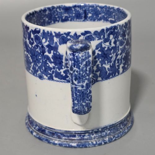 fig 1. A cylindrical blue and white transferware ceramic tankard featuring a floral upper border and a coat of arms crest with the text No 11.