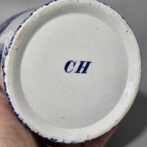 fig 3. A cylindrical blue and white transferware ceramic tankard featuring a floral upper border and a coat of arms crest with the text No 11.