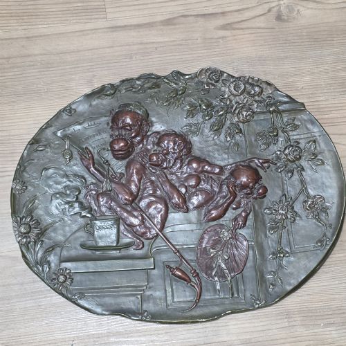 fig 2. An oval dark brown Austrian terracotta relief plaque depicting a satirical scene of an anthropomorphic monkey family framed by relief floral motifs.