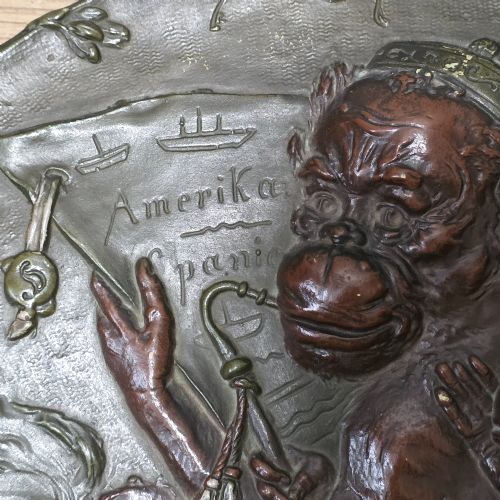 fig 4. An oval dark brown Austrian terracotta relief plaque depicting a satirical scene of an anthropomorphic monkey family framed by relief floral motifs.