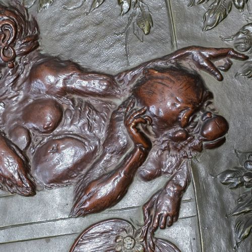 fig 5. An oval dark brown Austrian terracotta relief plaque depicting a satirical scene of an anthropomorphic monkey family framed by relief floral motifs.