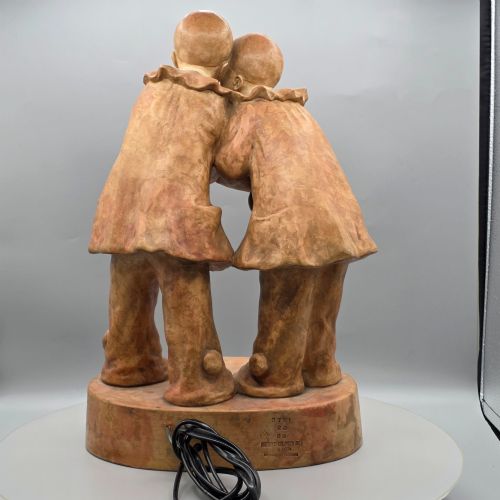 fig 1. A terracotta sculpture featuring two Pierrot figures in ruffled collars standing together on an oval plinth, designed as a lamp base.
