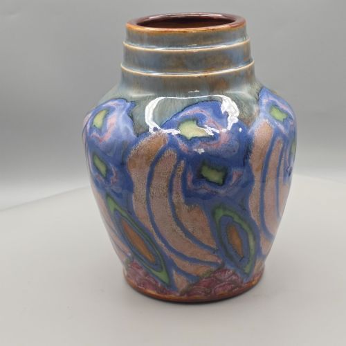fig 1. An Art Nouveau baluster-shaped stoneware vase with a stepped rim, featuring vibrant blue, pink, green, and ochre glazes forming abstract floral motifs.