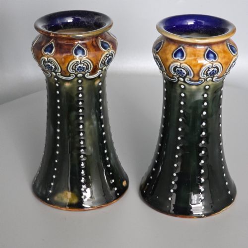 fig 1. A pair of 1920s Royal Doulton Art Nouveau stoneware vases featuring flared bases, mottled dark green and brown glazes, and beaded shoulder decorations with blue accents.