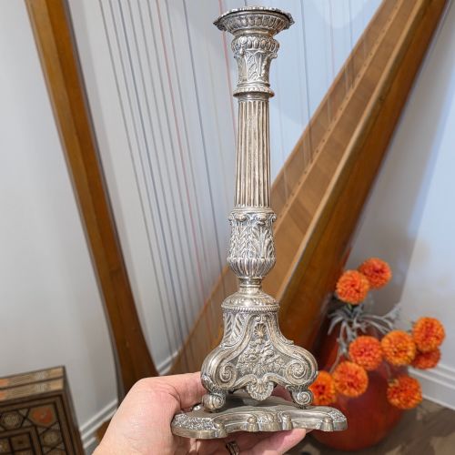 fig 3. A set of four silver candlesticks with fluted columns and ornate leaf details set on molded tripod bases.
