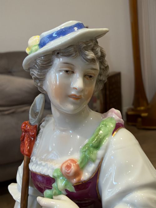 fig 1. A pair of antique hand-painted German porcelain figures depicting a shepherdess with a lamb and a shepherd holding a basket, set on circular gilded bases.