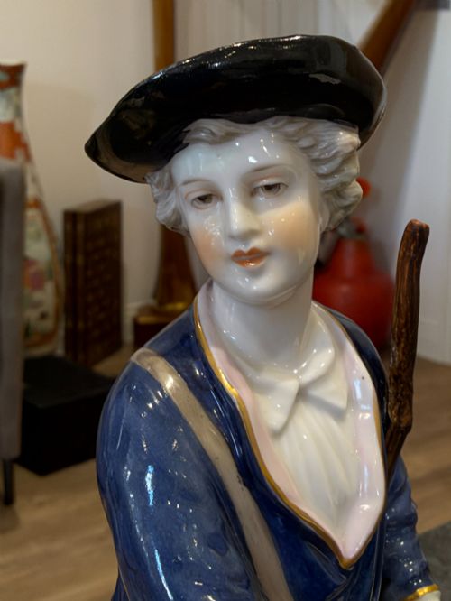 fig 2. A pair of antique hand-painted German porcelain figures depicting a shepherdess with a lamb and a shepherd holding a basket, set on circular gilded bases.